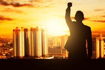 Silhouette of a businessman standing and raised hands