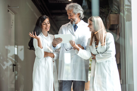 Team Of Confident Medical Experts. Doctor In A Conversation With Specialist. Man And Woman Doctor Having A Discussion In Hospital Hallway While Holding Digital Tablet.  Doctor Discussing Patient Case