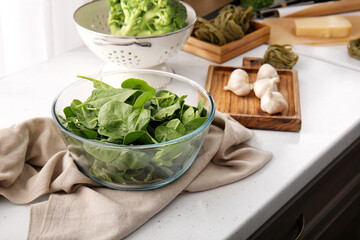 Bowl with fresh spinach on table in kitchen