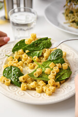Eating of healthy pasta with spinach at table