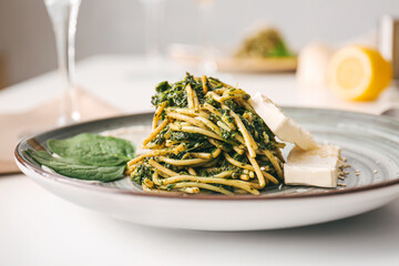 Plate with tasty pasta and spinach on table