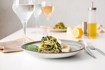 Plate with tasty pasta and spinach on table