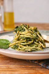 Plate with tasty pasta and spinach on table, closeup