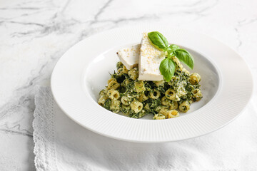 Plate with tasty pasta and spinach on table