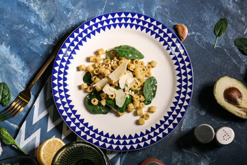 Plate with tasty pasta and spinach on color background