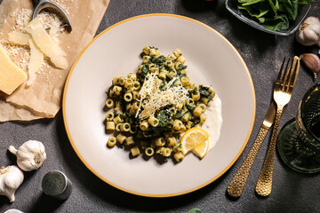 Plate with tasty pasta and spinach on table