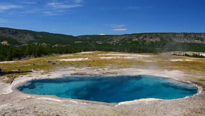 the deep blue gem pool hot spring in the cascade group on a sunny day in yellowstone national park, wyoming
