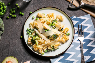 Plate with tasty pasta and vegetables on table