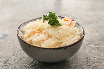 Bowl with tasty sauerkraut on grunge background