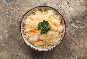 Bowl with tasty sauerkraut on grunge background