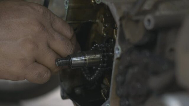 Mechanic put on a chain magnetic wheels on motorcycle engine mechanic, the motorbike in the shop, automatic motorbike repair