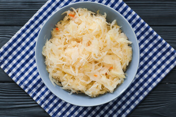 Bowl with tasty sauerkraut on dark wooden background
