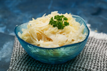 Bowl with tasty sauerkraut on color background
