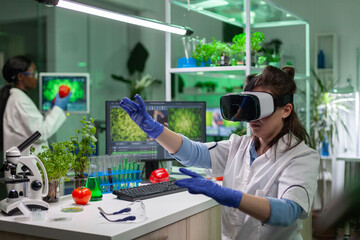 Scientist woman researcher wearing virtual reality headset developing new biotechnology for biological experiment. Medical team working in microbiology laboratory analyzing dna test.