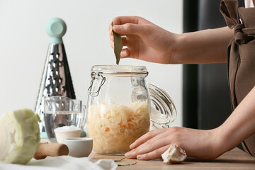 Woman preparing tasty sauerkraut at kitchen table, closeup