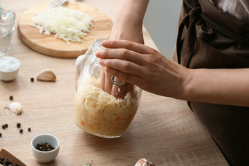 Woman preparing tasty sauerkraut at kitchen table, closeup