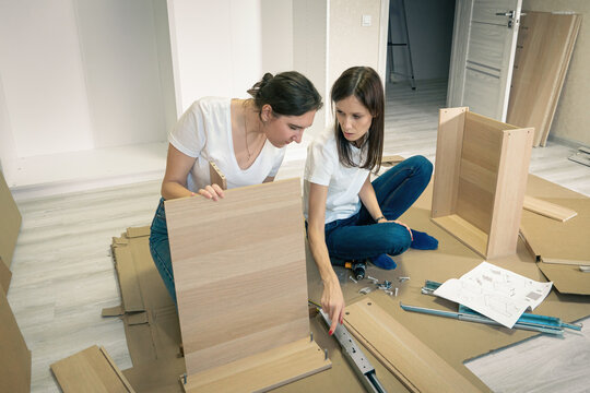 Woman Assembling Flat Pack Furniture DIY At Home On Floor. Bought Furniture Through Online Store