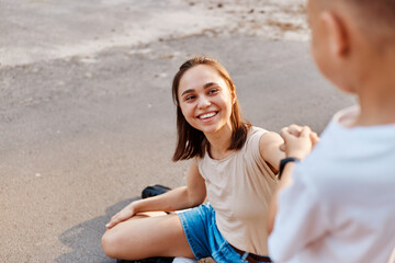 Young adult attractive mother with son on roller skates, active family concept. focus on smiling...
