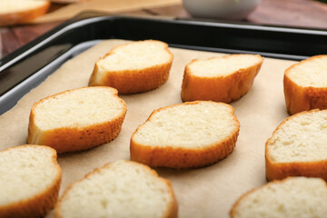 Baking sheet with slices of fresh bread on table, closeup