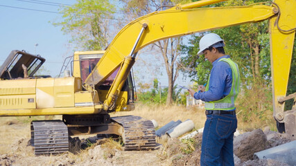 Construction worker controls digging of trench with  excavator on site.