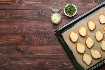 Baking sheet with slices of fresh bread on wooden background