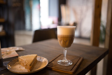Cappuccino and a slice of cake on a table in a cafe.