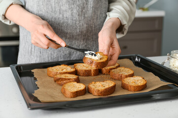 Female chef preparing toasts with cheese on kitchen table, closeup