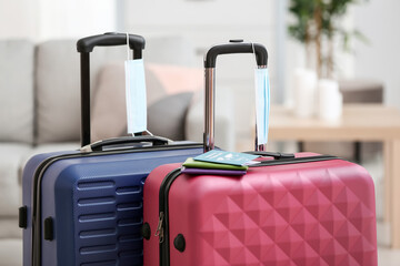 Packed suitcases with immune passport and medical masks in room