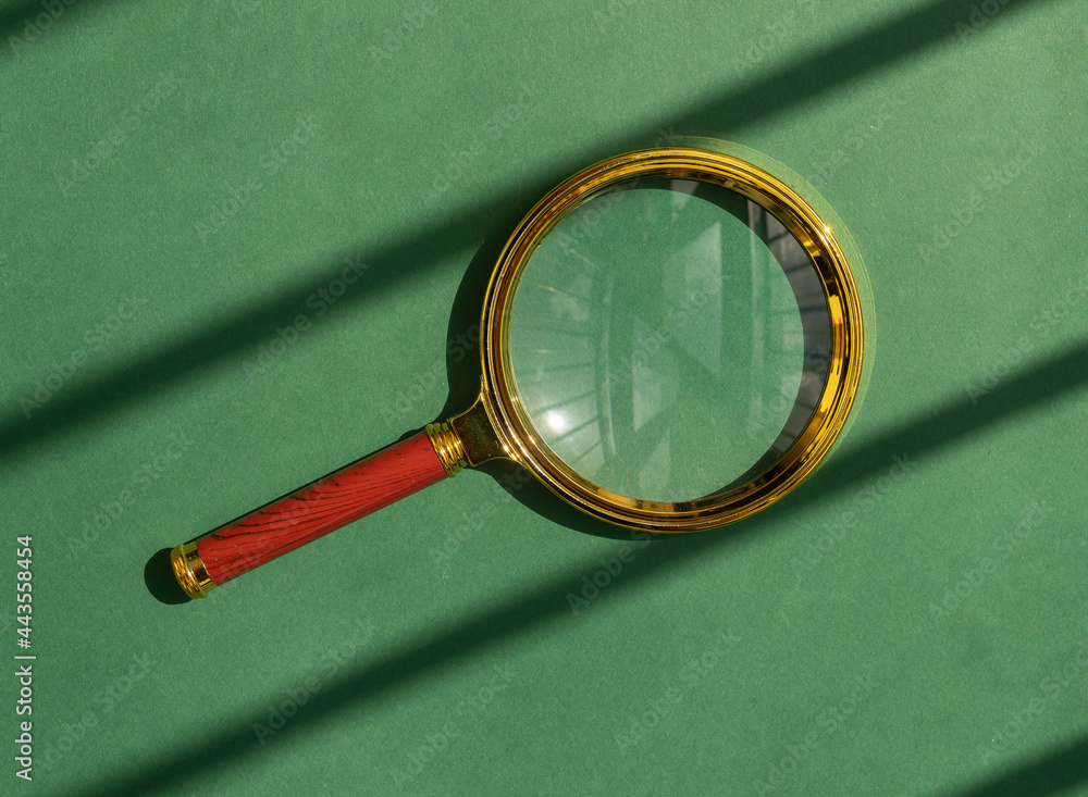 Poster magnifying glass over green background with sun light. magnifier as concept of finding answers.