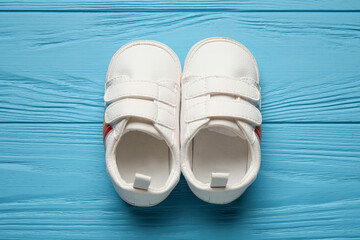 Stylish baby shoes on color wooden background