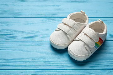 Stylish baby shoes on color wooden background, closeup