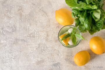 Glass of lemonade with basil on light background