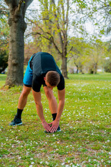 Fit man warming up doing squats stretching arms forward outdoors