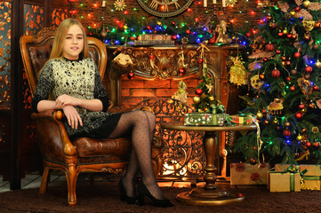 Portrait of cute happy girl sitting by Christmas tree