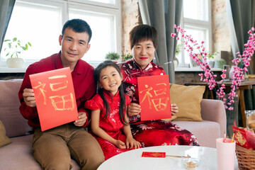 Cheerful Asian family with handmade new year postcards