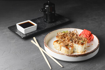 Tuna sushi in white dish served with soy and wasabi sauce, pickled ginger. Sushi set with tuna shavings on top.