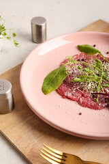 Plate with tasty veal carpaccio on light background