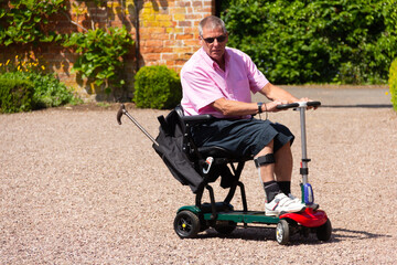Happy man enjoying the independence that a mobility scooter gives him to explore gardens on a...