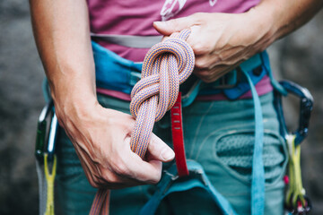 Rock climber wearing safety harness making a eight rope knot