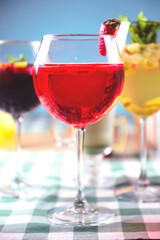 Set of alcoholic cocktails in raw on a wooden table with green plaid tablecloth.