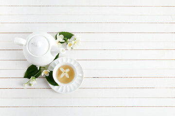 Fototapeta na wymiar Jasmine flowers and teapot on white wooden background. Herbal tea of jasmine flower. Flat lay.