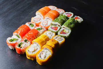 Sushi Set nigiri and sushi rolls served on black stone background. Japanese cuisine concept
