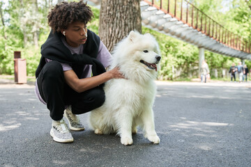 Teen man spending time with his pedigree dog in the summer street