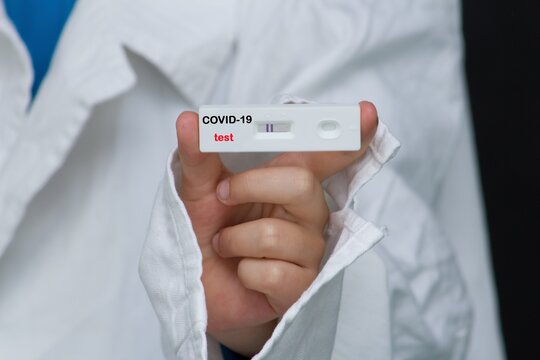 The doctor is holding a positive antigen test for covid. With this test, you can test yourself at home using saliva or a nasal swab.