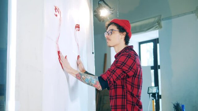 A man with tattoos is painting during art-therapy