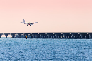 A light twin-engine propeller plane lands on a runway built in the sea. Concept of tourist excursions and civil aviation in the resort © EdNurg