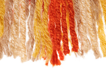 fringed edge of a small handmade rug or mat, woven from red and yellow wool threads, one object...