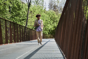 Man wearing earphones while walking at the summer park around the green nature