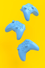 Flying gamer joysticks or gamepads on yellow background