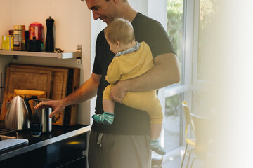 Father with kid making coffee in kitchen